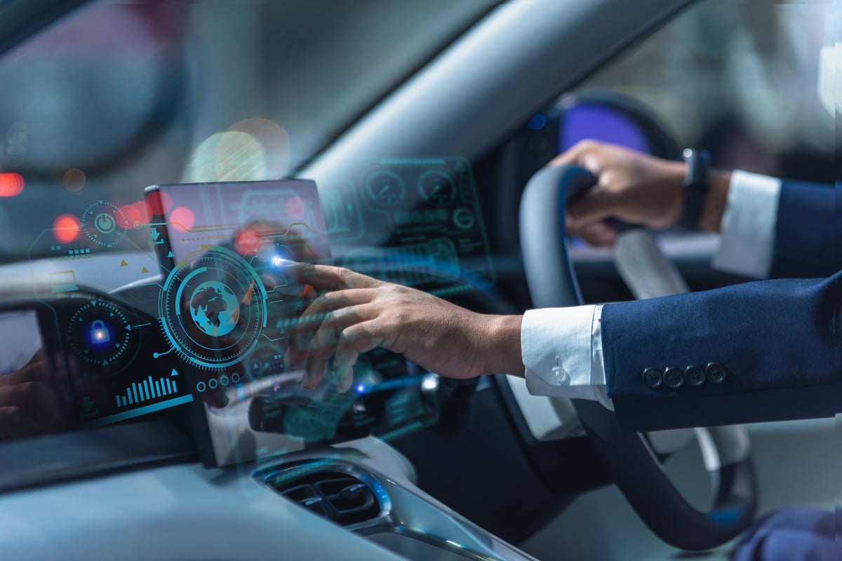 Modern car interior showing a businessman interacting with an advanced digital dashboard featuring holographic controls, navigation data, and smart driving technology.